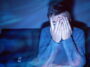 Man covering his eyes while watching TV.
